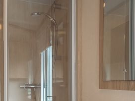 A shower enclosure and mirror in the bathroom at Willow in Swanage