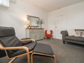 A living room with a chair, sofa, and cabinet at Bluebell Cottage in Brayton
