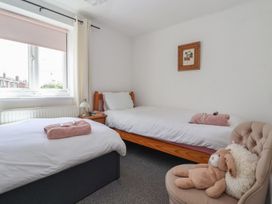 A bedroom with two beds and a chair at Bluebell Cottage in Brayton