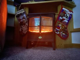 An electric stove with glowing effect and Christmas stockings at Foxglove Barn South Brent