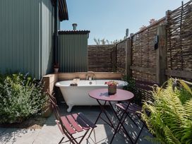 An outdoor area with a bathtub and seating at Hurdlemakers Hut in Piddletrenthide
