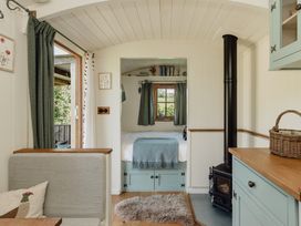 A living room with a bed and stove at Hurdlemakers Hut in Piddletrenthide