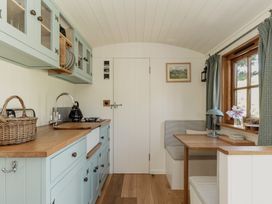 A kitchen with cabinets and a dining table at Hurdlemakers Hut in Piddletrenthide
