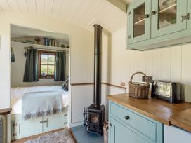 A living room with a bed and a stove at Hurdlemakers Hut in Piddletrenthide