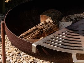 A fire pit with wood inside and a metal grate at Hurdlemakers Hut in Piddletrenthide