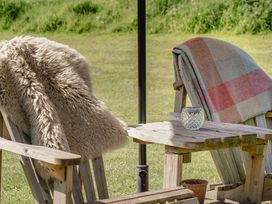 A chair with a blanket and a table in an outdoor seating area at Hurdlemakers Hut in Piddletrenthide