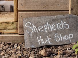 A sign for Shepherds Hut Shop near wooden structure