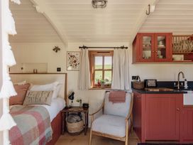 A tiny house interior with a bed, chair, and kitchen at Spindleberry Hut in Piddletrenthide