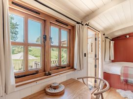 A bedroom with windows, a door, table, chair, and bed at Spindleberry Hut in Piddletrenthide