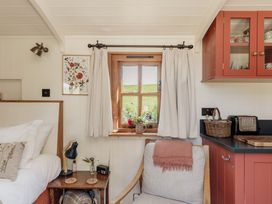 A bedroom with a window, chair, and kitchen cabinet at Spindleberry Hut in Piddletrenthide