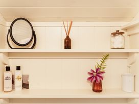 A bathroom shelf with a mirror, toiletries, and decorative items at Spindleberry Hut in Piddletrenthide