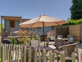 A garden with a table, chairs, and an umbrella at Spindleberry Hut in Piddletrenthide