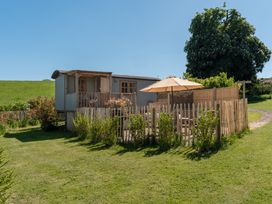 A garden with a shepherd's hut and patio area at Spindleberry Hut in Piddletrenthide