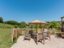 An outdoor area with a table, chairs, and a barbecue at Spindleberry Hut in Piddletrenthide