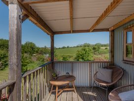 A balcony with a table and chairs at Spindleberry Hut in Piddletrenthide