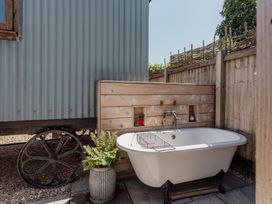 An outdoor bathing area with a bathtub and wooden structure at Spindleberry Hut in Piddletrenthide