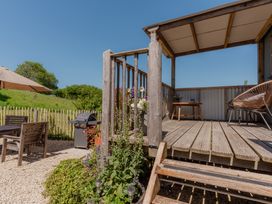 An outdoor area with a wooden deck and table at Spindleberry Hut in Piddletrenthide