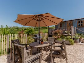 An outdoor seating area with a table and chairs and a grill at Spindleberry Hut Piddletrenthide