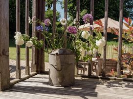 A watering can with flowers on a deck at Spindleberry Hut in Piddletrenthide
