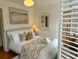 A bedroom with a bed, pillows, a bedside table with a lamp and a wall mirror at Bodillys Cottage in Newlyn