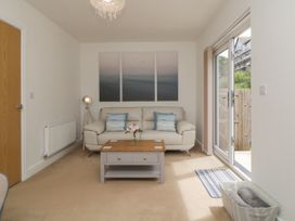 A living room with a sofa pillows coffee table and glass door leading outside at Ocean Retreat in Goodrington near Paignton