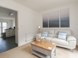 A living room with a white sofa a wooden coffee table and a triptych sea painting on the wall at Ocean Retreat in Goodrington near Paignton