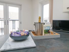 A kitchen counter with a bowl of snacks and a tray holding a bottle in an ice bucket glasses and a postcard at Ocean Retreat in Goodrington near Paignton