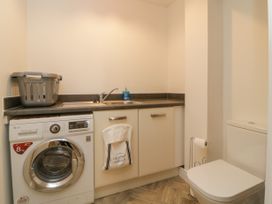 A laundry room with a washing machine a sink a countertop a laundry basket and a toilet at Ocean Retreat in Goodrington near Paignton