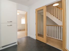 A hallway with a closed cupboard door and an open wooden door leading to a stairwell at Ocean Retreat in Goodrington near Paignton