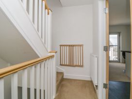 A staircase landing with white railings a wooden baby gate on the wall and an open door leading to a room with a window at Ocean Retreat in Goodrington near Paignton