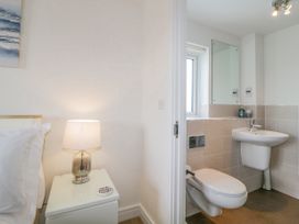 A bedside table with a lamp next to a bed and a bathroom with a toilet and sink at Ocean Retreat in Goodrington near Paignton