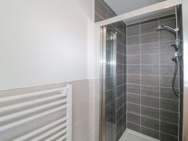 A shower area with gray tiled walls and a handheld showerhead next to a white heated towel rack at Ocean Retreat in Goodrington near Paignton