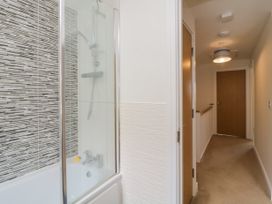 A hallway with a closed wooden door and a bathroom with a bathtub and shower at Ocean Retreat in Goodrington near Paignton