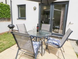 An outdoor patio with a round glass table and four chairs on a tiled floor at Ocean Retreat in Goodrington near Paignton