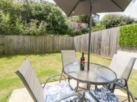 A garden with a glass table surrounded by four chairs and an umbrella at Ocean Retreat in Goodrington near Paignton