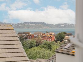 A view of rooftops trees and a body of water with hills in the background at Ocean Retreat in Goodrington near Paignton