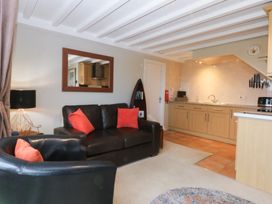 A living room with a sofa and kitchen area at Oak Cottage in Dinas Dinlle near Caernarfon