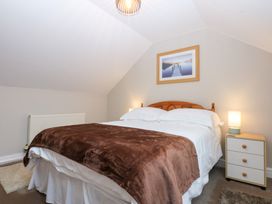 A bedroom with a bed and nightstand at Oak Cottage in Dinas Dinlle near Caernarfon