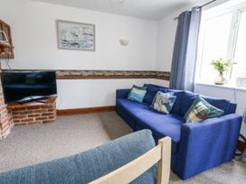 A living room with a blue sofa and television at Saddlers Cottage in Weymouth