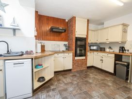 A kitchen with wooden countertop and appliances at Saddlers Cottage in Weymouth