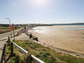 A beach with a road and houses nearby at The Waves Little Haven near Broad Haven