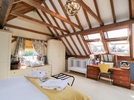 A bedroom with a bed, dresser, crib, and windows at The Old Byre in Woodfalls