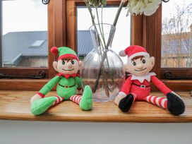 Two elf plush toys and a vase on a wooden shelf at The Old Byre in Woodfalls