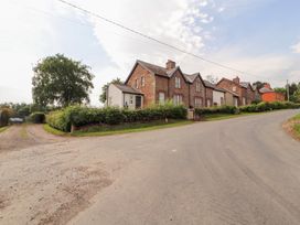 Houses along a road with green grass and trees at Rose Bank Cottage Dalston