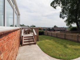 A garden with a deck and furniture at Rose Bank Cottage in Dalston