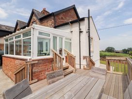 A conservatory attached to a house with a wooden deck at Rose Bank Cottage Dalston
