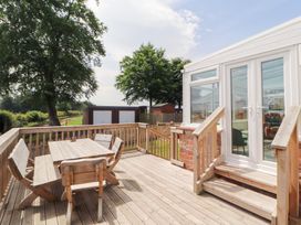 A deck with a wooden table and chairs at Rose Bank Cottage in Dalston