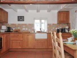 A kitchen with wooden cabinets and a dining table at 3 River View in Looe