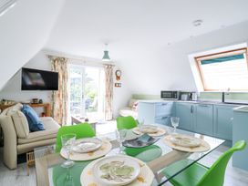 A kitchen and dining area with blue cabinets green chairs and a beige sofa at Kingfisher in Isleham