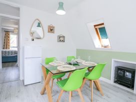 A dining room with a glass table and green chairs near a refrigerator and a small stove at Kingfisher in Isleham